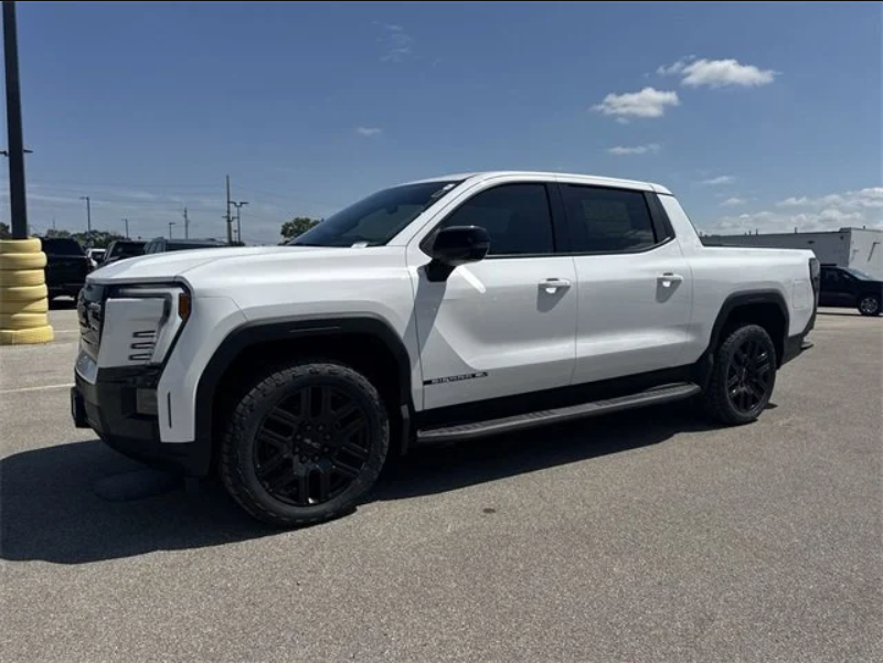 2026 GMC Sierra EV Elevation Extended Range in Summit White parked at Dave Sinclair Buick GMC in St. Louis, featuring black wheels and crew cab design.