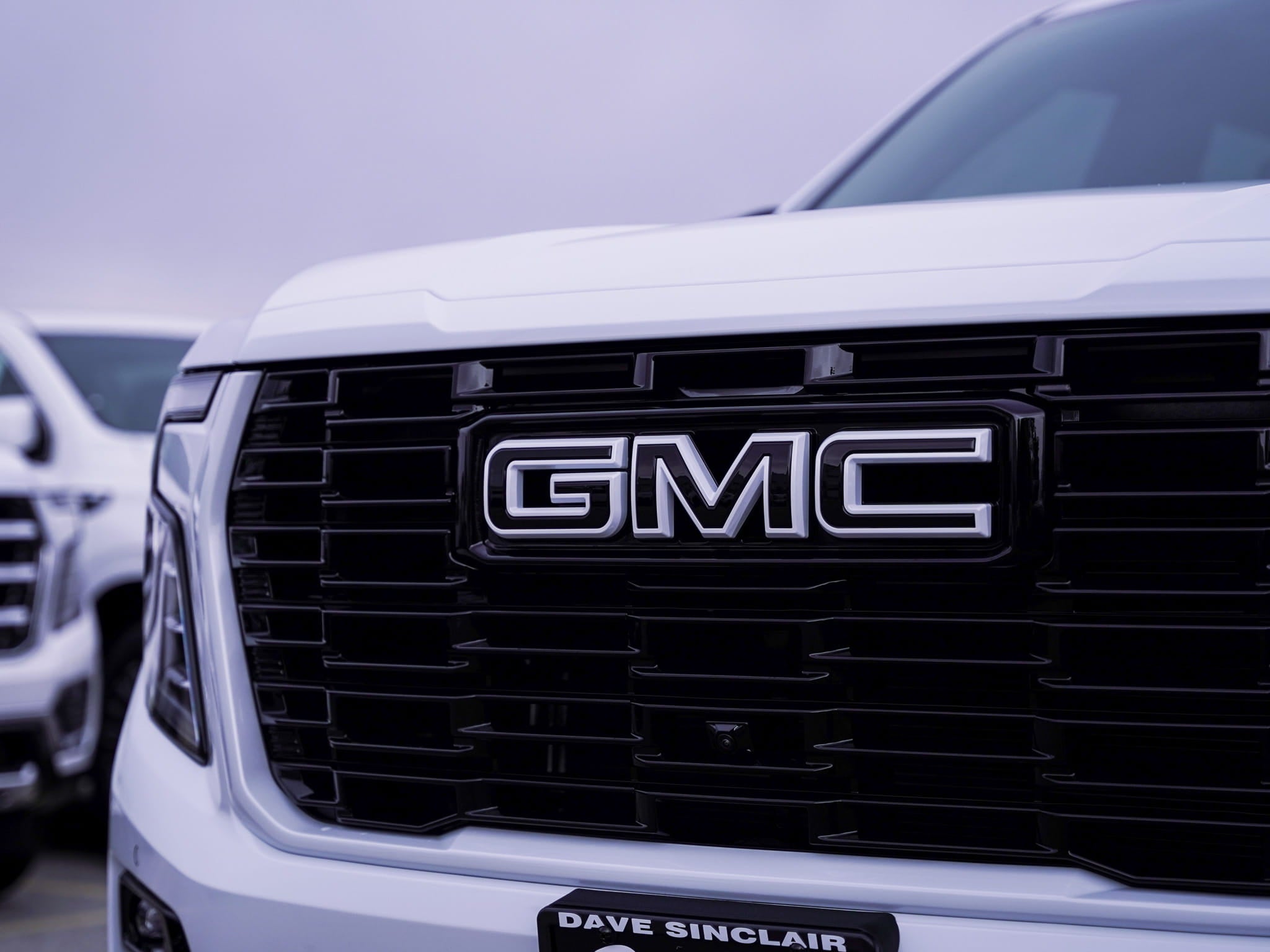 Close-up of the blacked-out front grille and GMC emblem on a custom 2026 GMC Yukon Denali in Glacier White Tricoat after full chrome delete